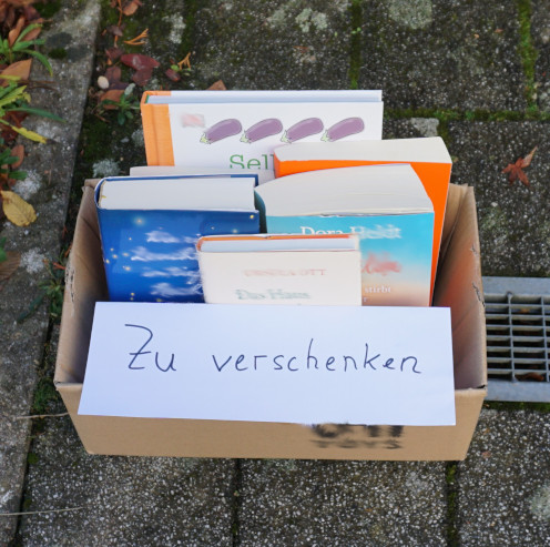 Kleiner Karton mit Büchern und einem Schild "zu verschenken"